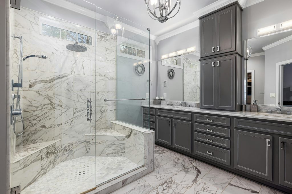 Spacious bathroom featuring elegant marble shower and dark cabinetry.